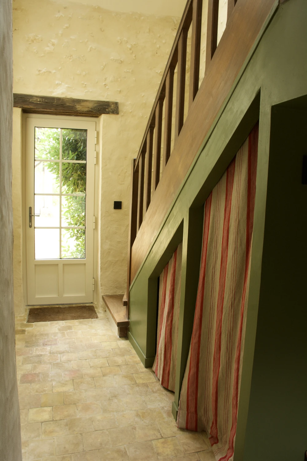 L'escalier de bois et son soubassement vert, la porte vitrée ouverte sur le jardin
